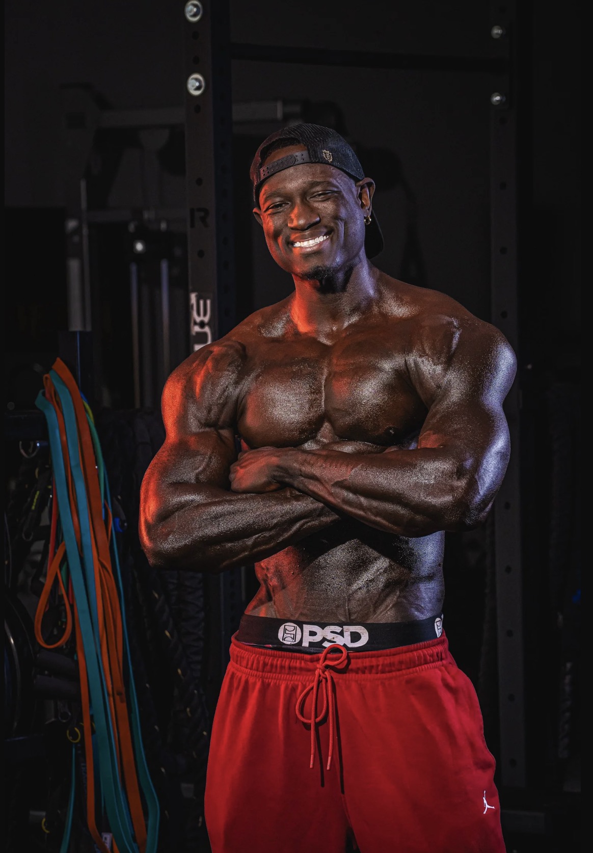Coach JR smiling with arms crossed in the gym